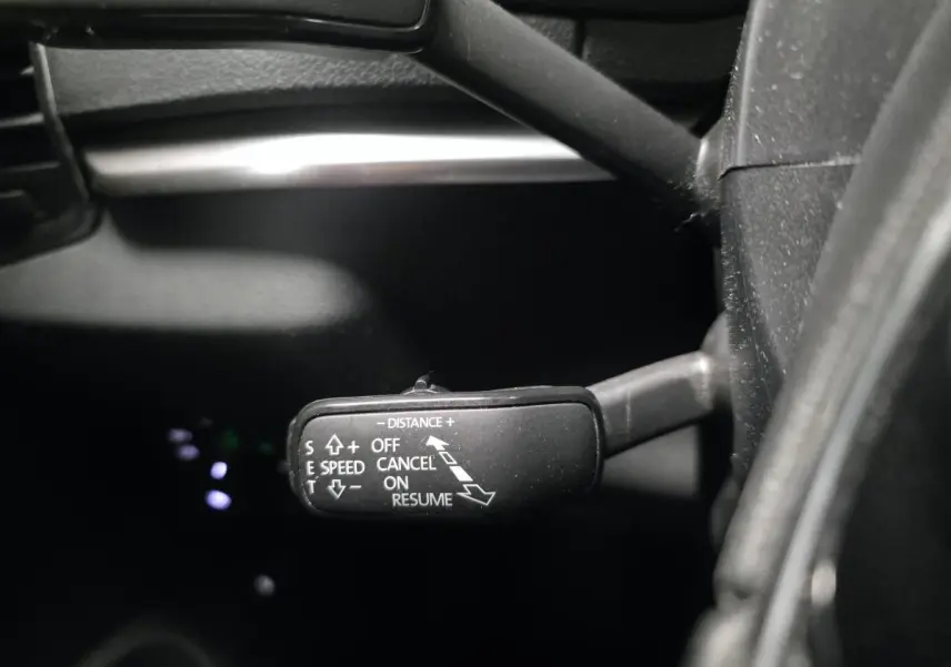 Gros plan sur le commodo de régulateur de vitesse dans l’habitacle noir du Skoda Karoq 2023.