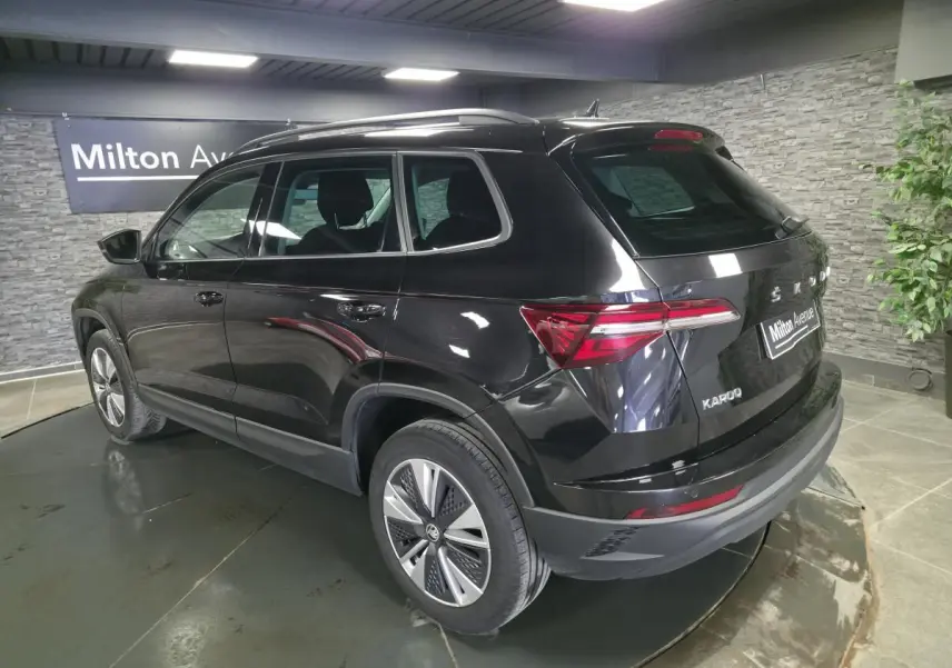 Vue 3/4 arrière droite d'un Skoda Karoq noir 2023 avec jantes alliage et feux arrière LED dans un showroom.