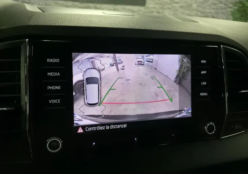 Écran central du Skoda Karoq noir montrant la caméra de recul avec guidage de trajectoire en intérieur de garage.