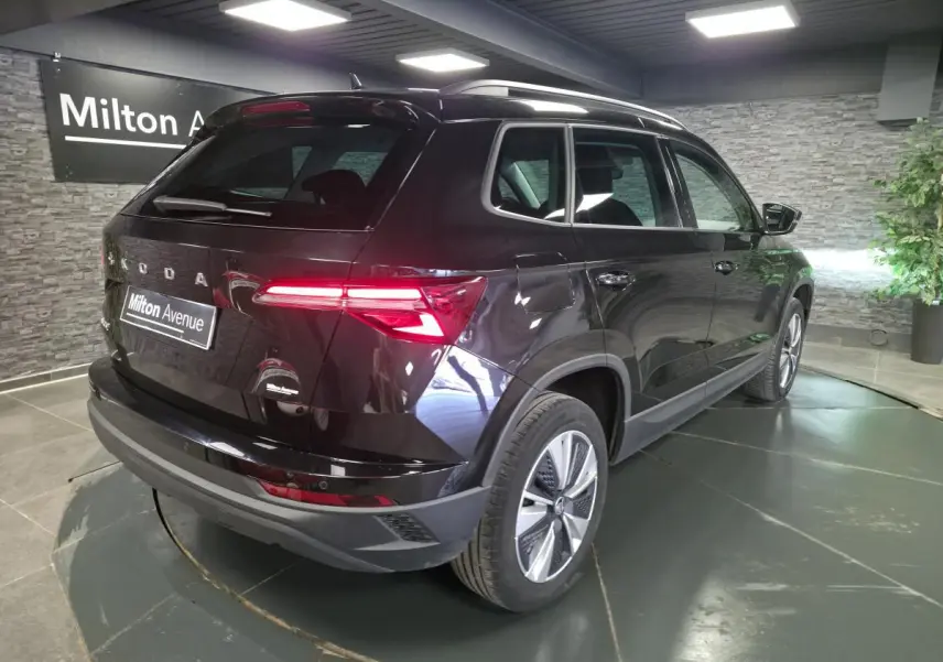 Vue 3/4 arrière droite d'un Skoda Karoq noir 2023 avec feux arrière LED allumés et jantes alliage 17 pouces.