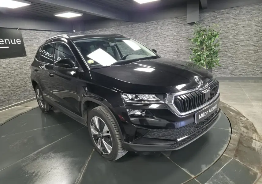 Vue 3/4 avant d'un Skoda Karoq noir avec calandre chromée et jantes alliage 17 pouces dans un showroom.