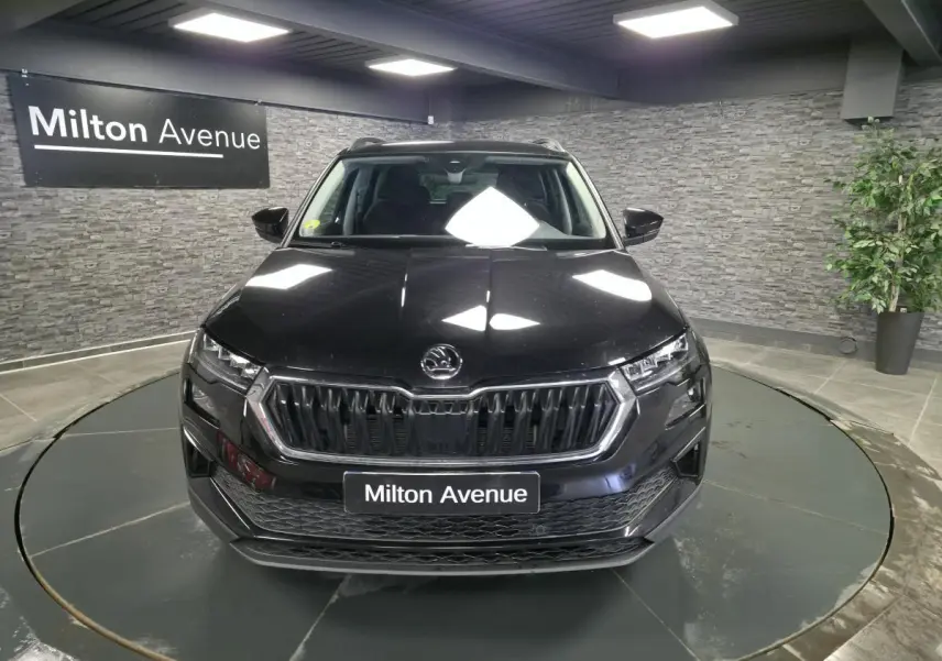 Vue avant d'un Skoda Karoq noir 2023 avec calandre chromée et feux LED dans un showroom.