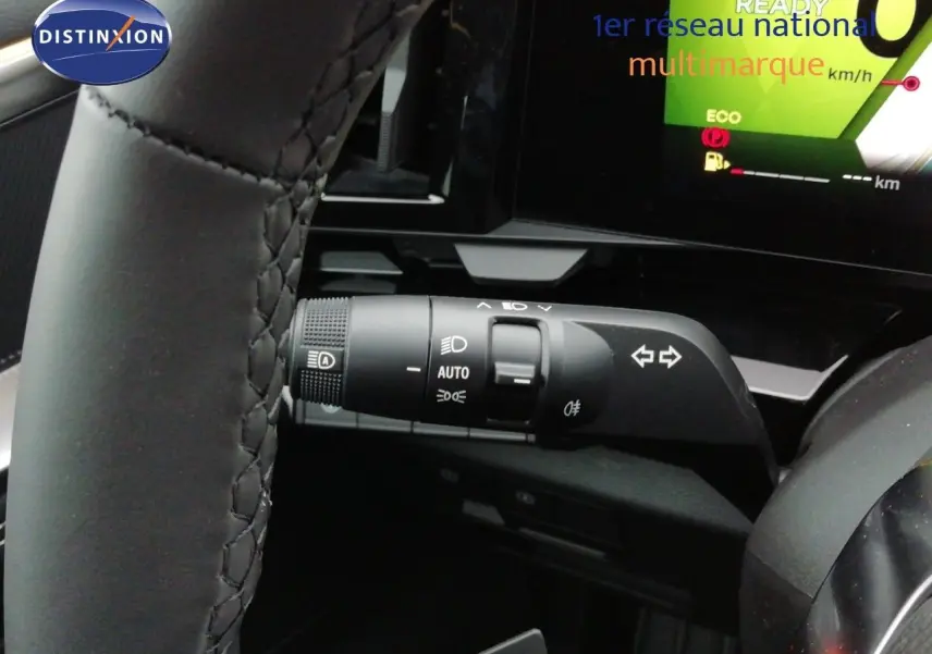 Gros plan sur la manette de clignotants et feux du Renault Austral noir étoile métal, avec tableau de bord digital en arrière-plan.