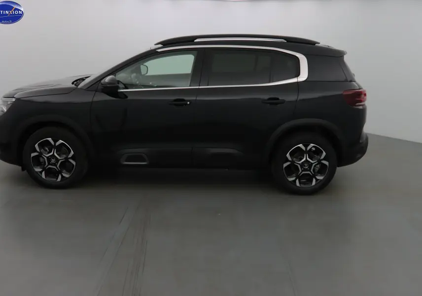 Profil côté gauche d'un Citroën C5 Aircross noir métallisé avec jantes biton et barres de toit visibles.