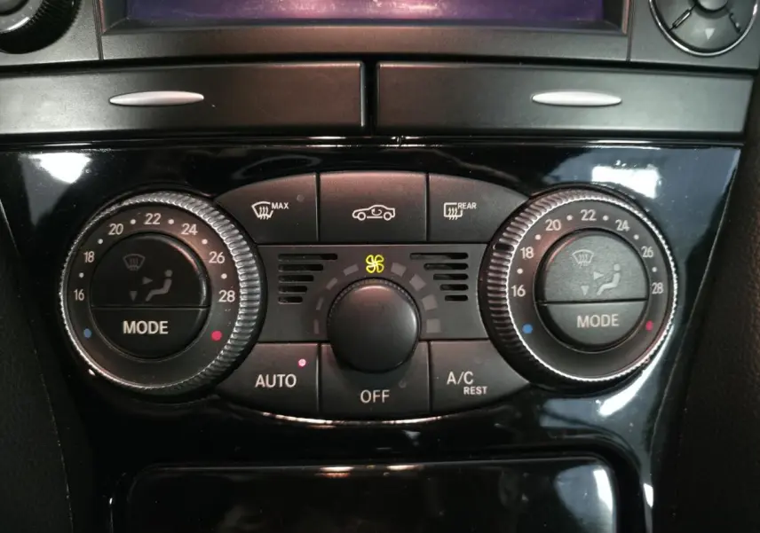 Gros plan sur la console centrale noire du Mercedes SL 500 2008, mettant en valeur les commandes de climatisation automatique.