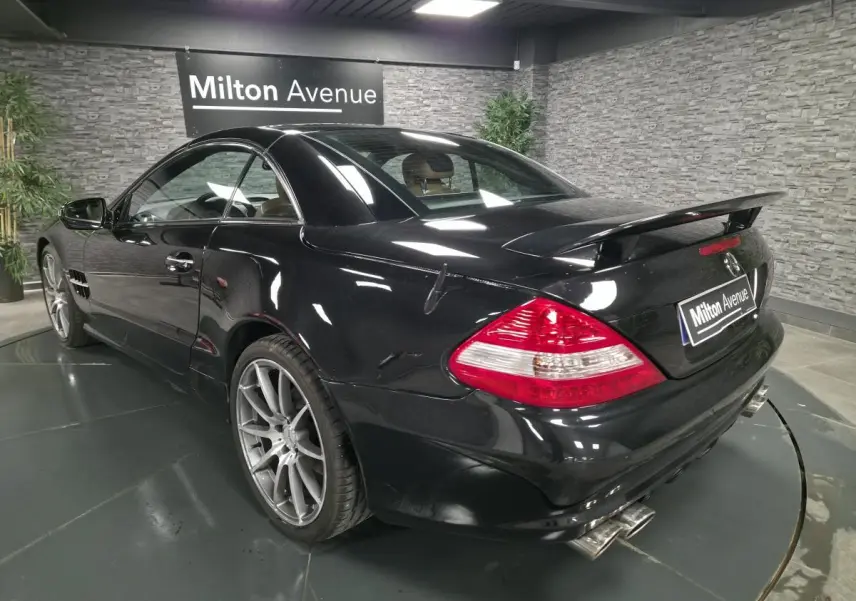 Mercedes SL 500 noir vu en 3/4 arrière droit, avec jantes alliage 19 pouces et aileron arrière AMG.