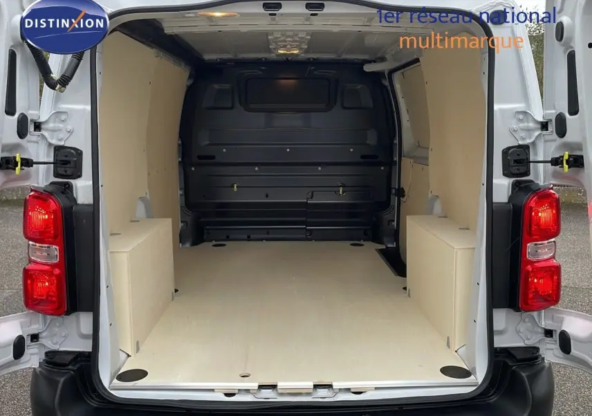 Vue arrière du Peugeot Expert Fourgon blanc 2025 montrant l'espace de chargement aménagé avec revêtement bois clair.