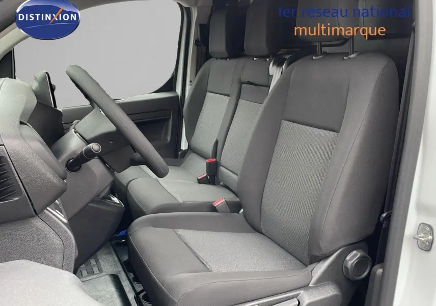 Intérieur du Peugeot Expert Fourgon 2025 vu côté conducteur, sièges tissu gris, volant et tableau de bord visibles.