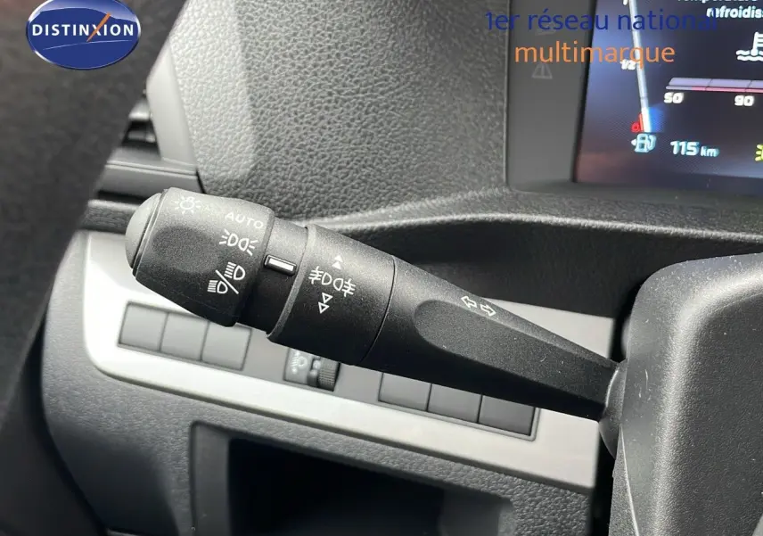 Gros plan sur le commodo des phares et clignotants du Peugeot Expert Fourgon blanc, tableau de bord en arrière-plan.