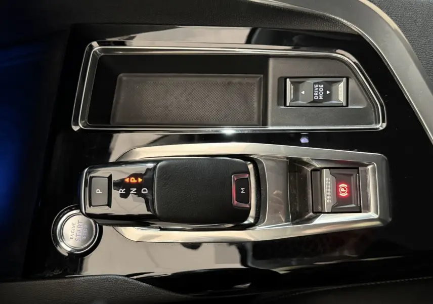 Vue rapprochée de la console centrale noire brillante du Peugeot 5008 2021 avec levier de boîte auto et bouton start/stop.
