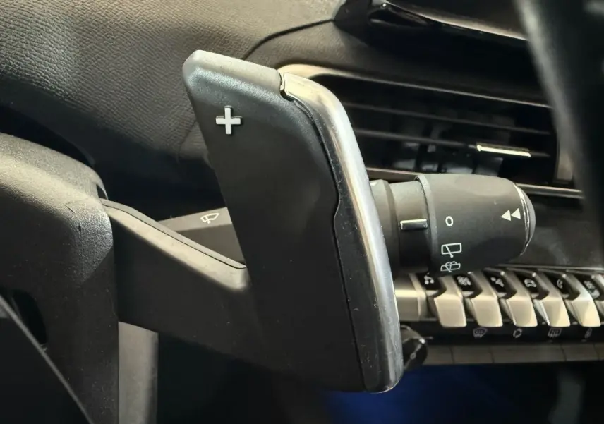 Gros plan sur la palette de changement de vitesse droite dans l’habitacle noir du Peugeot 5008 gris clair 2021.