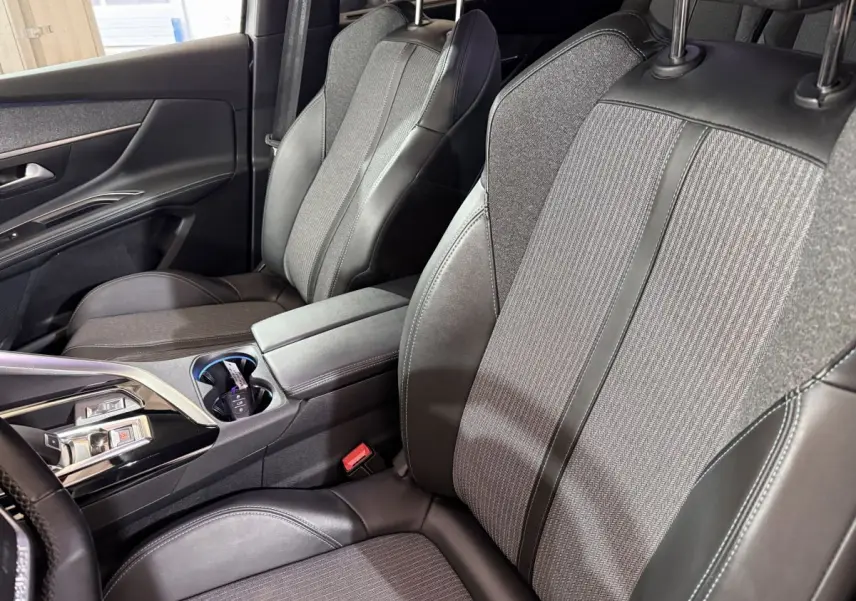 Vue intérieure côté avant droit du Peugeot 5008 2021, sièges tissu et cuir gris avec console centrale et commandes modernes.