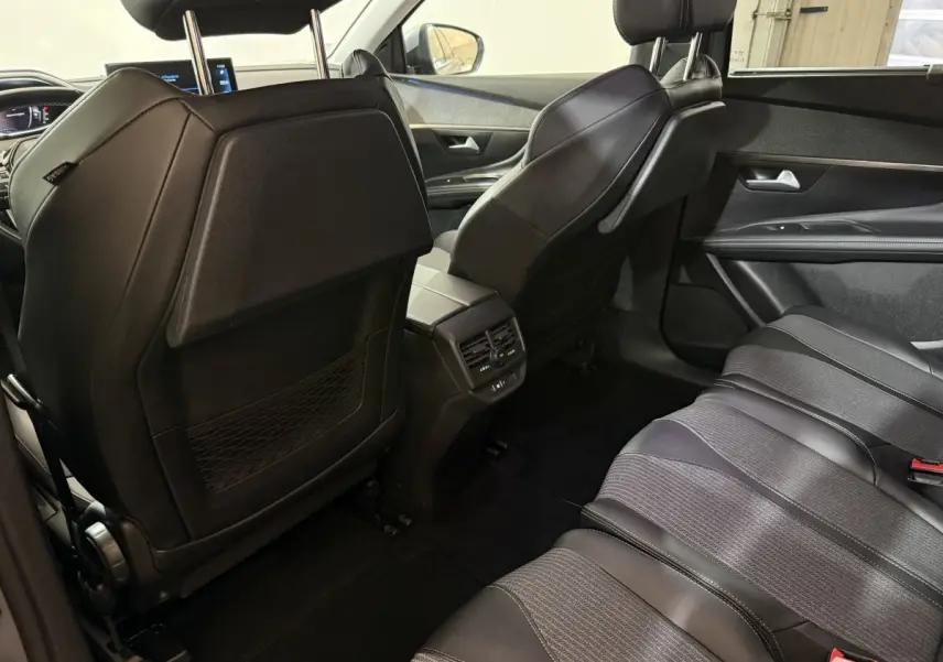 Vue intérieure arrière droite du Peugeot 5008 gris clair, sièges en cuir noir et console centrale avec aérateurs et ports USB.