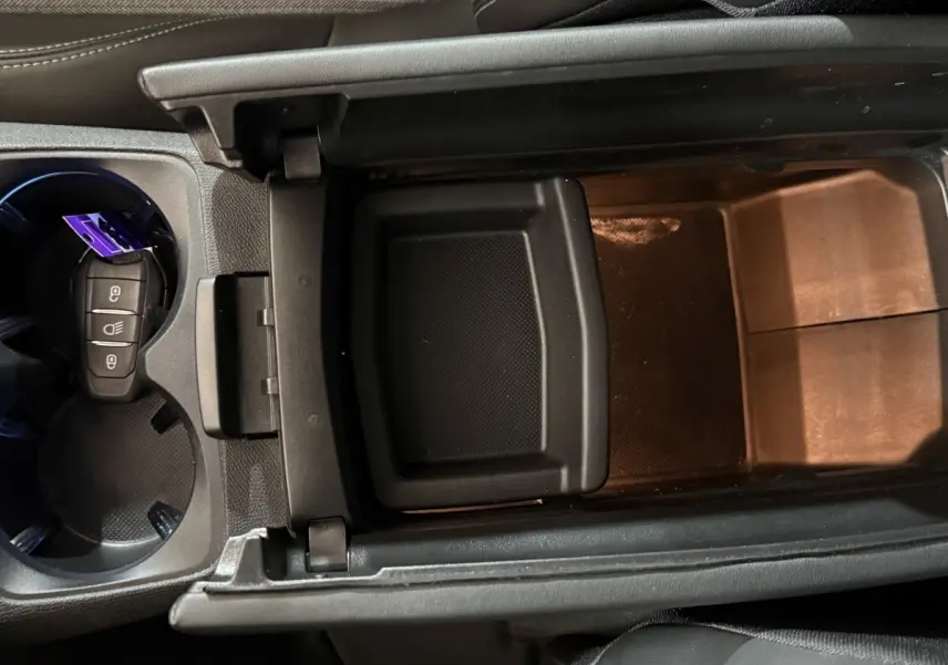 Vue plongeante sur le rangement central noir et porte-clés dans les porte-gobelets du Peugeot 5008 gris clair 2021.