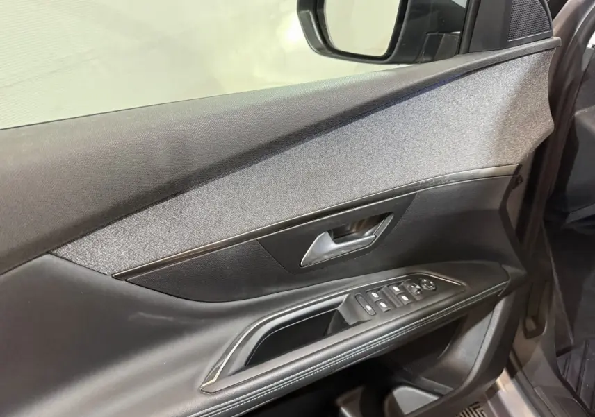 Vue intérieure côté gauche de la porte avant du Peugeot 5008 gris clair, avec commandes de vitres et rétroviseur.