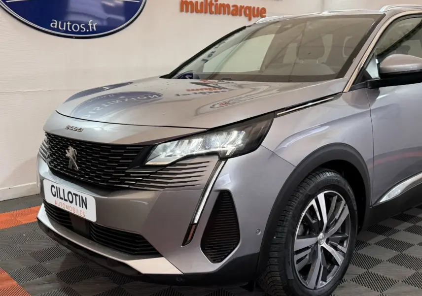 Vue 3/4 avant droit d’un Peugeot 5008 gris clair avec phares LED et calandre noire texturée.