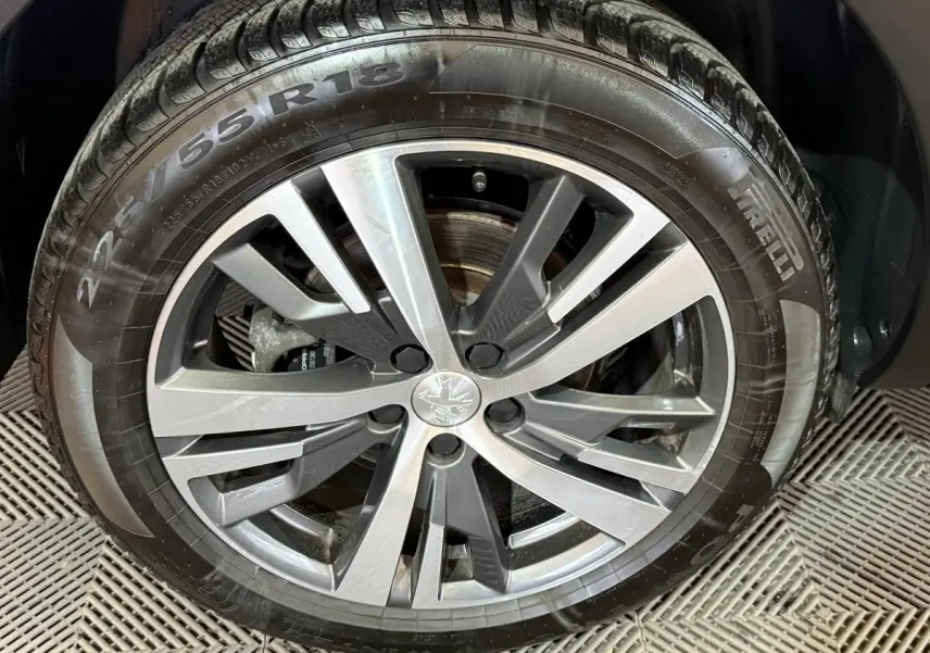 Gros plan sur la jante alliage gris et noir avec logo Peugeot, montée sur pneu Pirelli 225/55 R18 du 5008 gris clair.