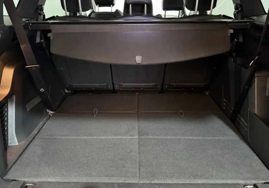 Coffre spacieux du Peugeot 5008 gris clair vu de l'arrière avec banquette arrière rabattue et cache-bagages déployé.