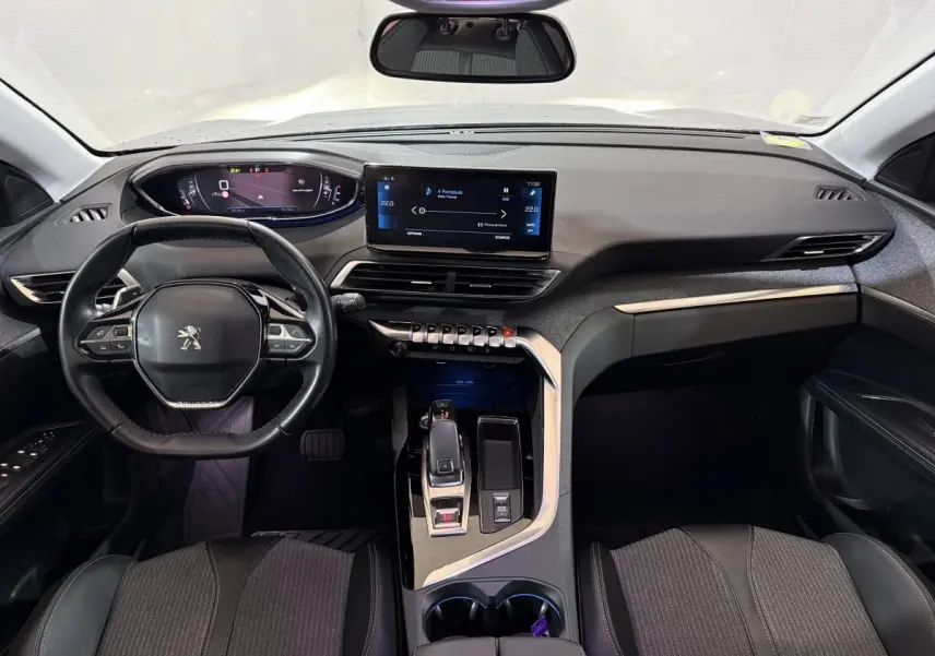 Vue intérieure avant du Peugeot 5008 gris clair, tableau de bord moderne avec écran tactile central et volant compact cuir.