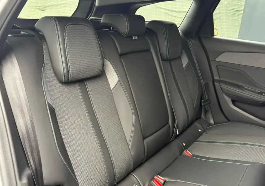 Vue intérieure des sièges arrière en cuir noir avec surpiqûres contrastantes dans une Peugeot 308 SW Hybrid 2025.