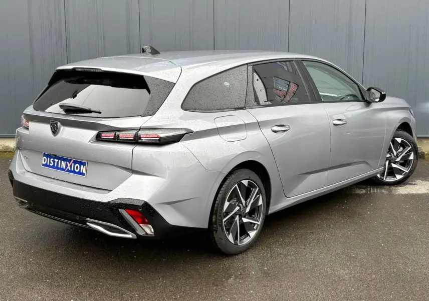 Vue 3/4 arrière droite d'une Peugeot 308 SW Hybrid gris Artense avec jantes alliage et vitres surteintées.