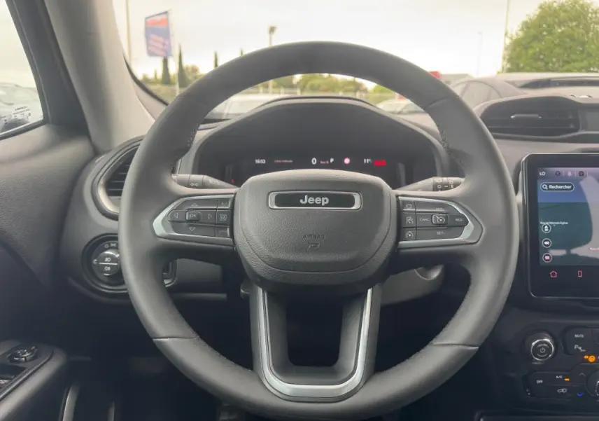 Vue centrée sur le volant du Jeep Renegade 2024, intérieur noir avec écran tactile et commandes au volant visibles.