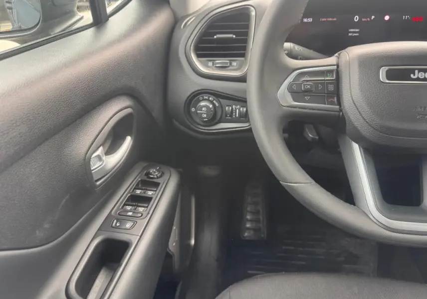 Vue intérieure côté conducteur du Jeep Renegade 2024, volant, commandes des vitres et tableau de bord partiel visibles.
