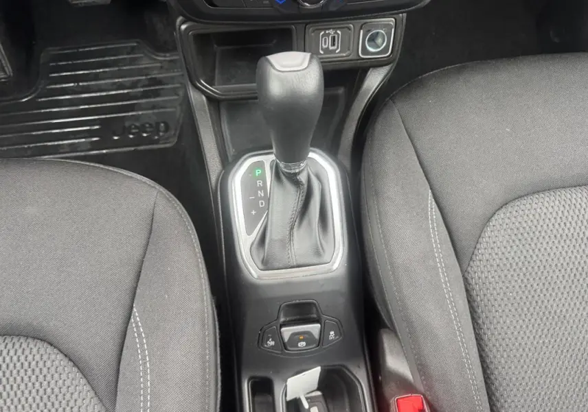 Vue rapprochée de la console centrale avec levier de vitesse automatique et sièges noirs du Jeep Renegade 2024.