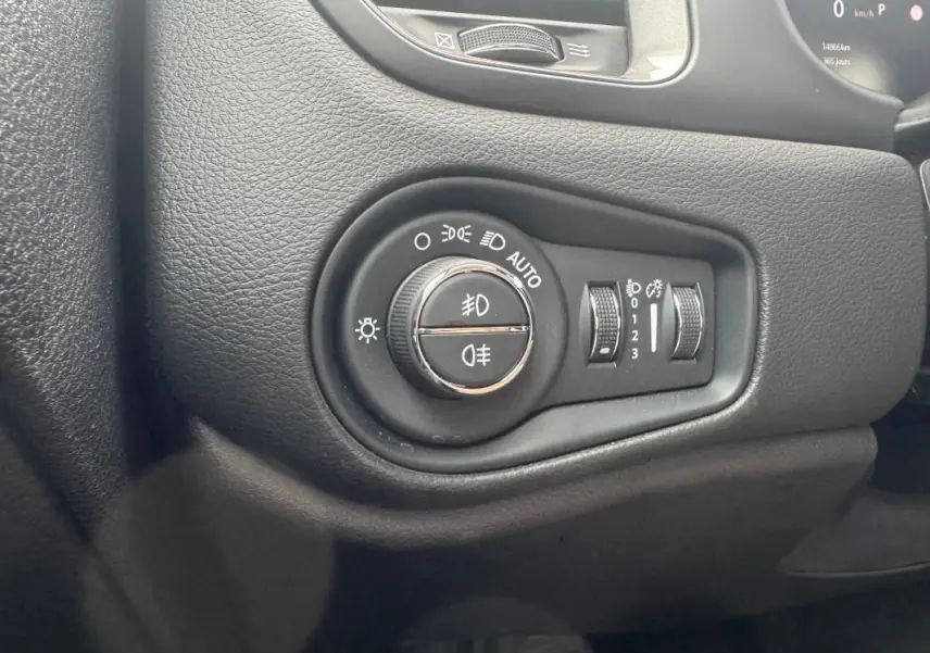 Gros plan sur le panneau de commande des phares du Jeep Renegade 2024, avec molette et réglages lumineux intégrés.