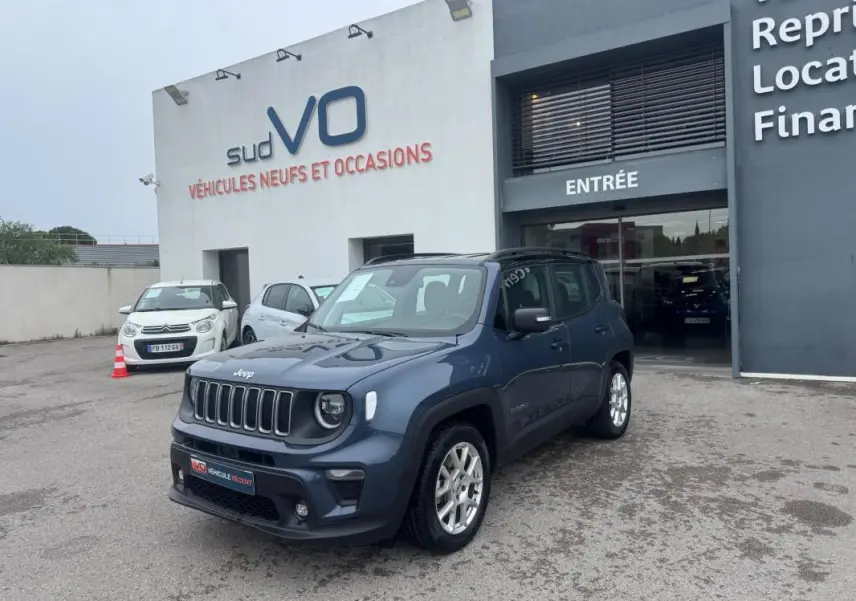 Jeep Renegade bleu en 3/4 avant droit, avec jantes alliage 17 pouces, stationné devant un concessionnaire.