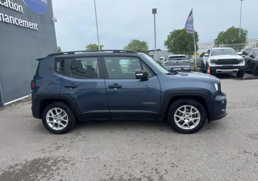 Jeep Renegade bleu en profil droit, avec barres de toit et jantes alliage 17 pouces visibles sur parking.