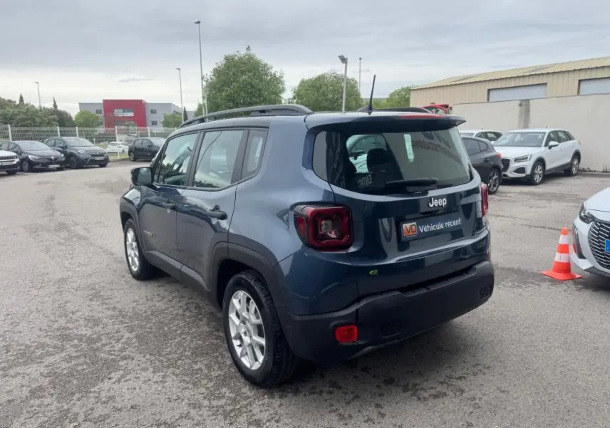 Jeep Renegade bleu en 3/4 arrière droit, avec barres de toit et jantes alliage 17 pouces visibles.
