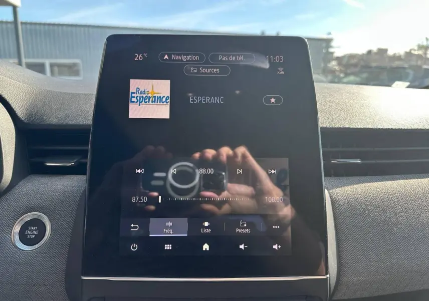 Écran tactile central de la Renault Clio 2025 affichant la radio, avec bouton Start/Stop visible à gauche.
