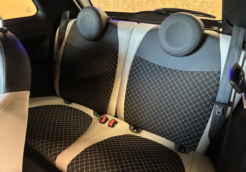Vue intérieure arrière des sièges arrière en tissu noir à motifs blancs et cuir beige d'une FIAT 500 blanche de 2021.