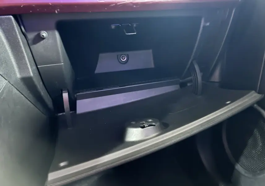 Gros plan sur la boîte à gants ouverte de la Fiat 500 blanche, intérieur noir avec détails fonctionnels visibles.