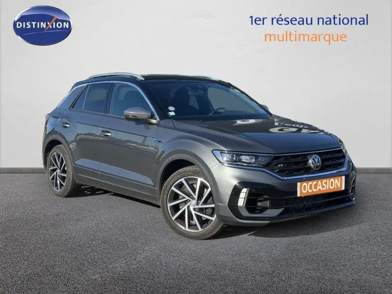 Volkswagen T-Roc gris métallisé en vue 3/4 avant droit avec jantes alliage et calandre noire sportive.