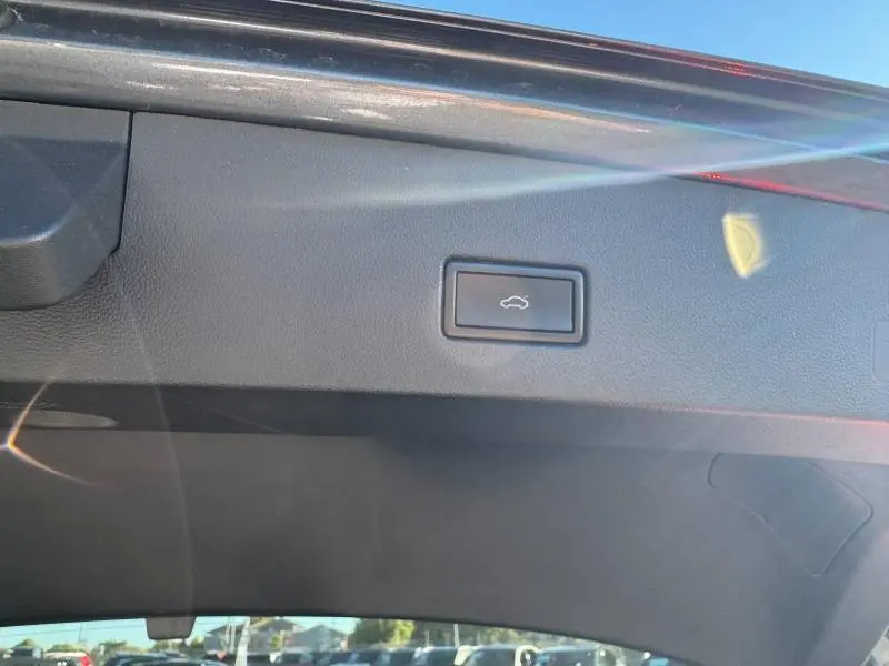 Bouton d'ouverture électrique du coffre sur la garniture intérieure noire du hayon arrière du Volkswagen T-Roc.