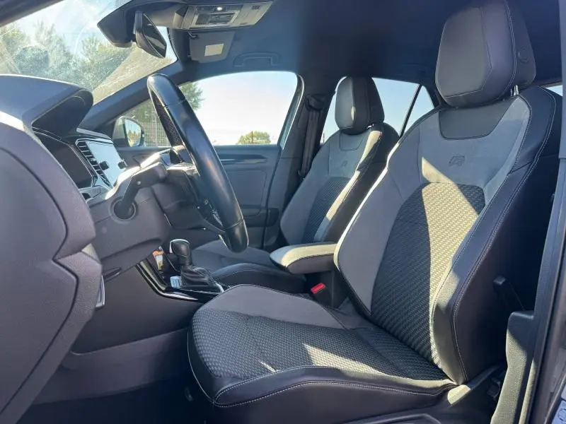 Vue intérieure côté conducteur du Volkswagen T-Roc 2.0 TSI 300ch R, sièges sport tissu/simili-cuir noirs avec surpiqûres blanches.