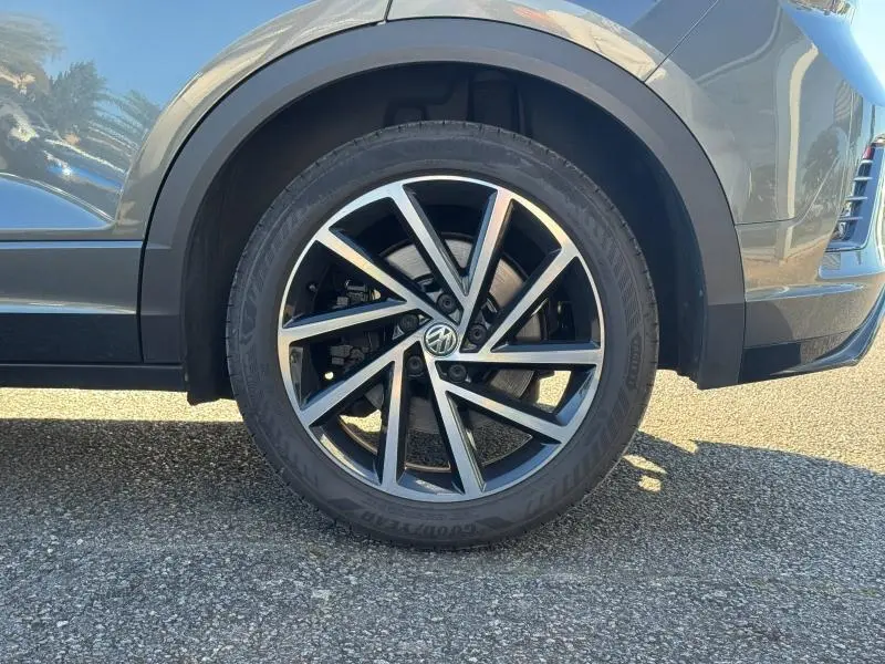 Gros plan sur la roue avant gauche du Volkswagen T-Roc gris, avec jante alliage noir et argent au design dynamique.