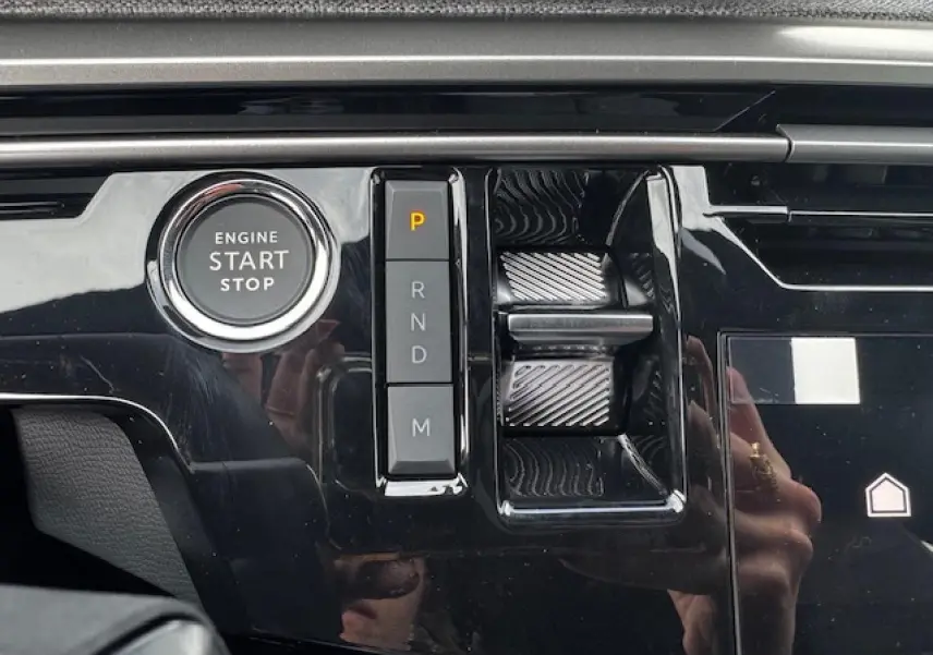 Gros plan sur la console centrale noire brillante du Peugeot 5008 2025 avec bouton start/stop et sélecteur de boîte auto.