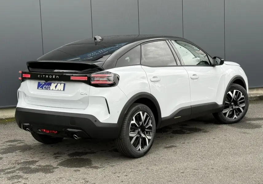 Vue 3/4 arrière droite d'une Citroën C4 hybride blanche Okénite avec toit noir Perla Nera et jantes alliage 18 pouces.
