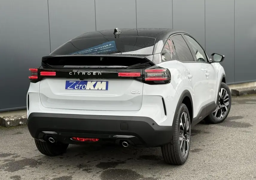 Vue 3/4 arrière droite d'une Citroën C4 blanche Okénite avec toit noir Perla Nera et feux arrière LED allumés.