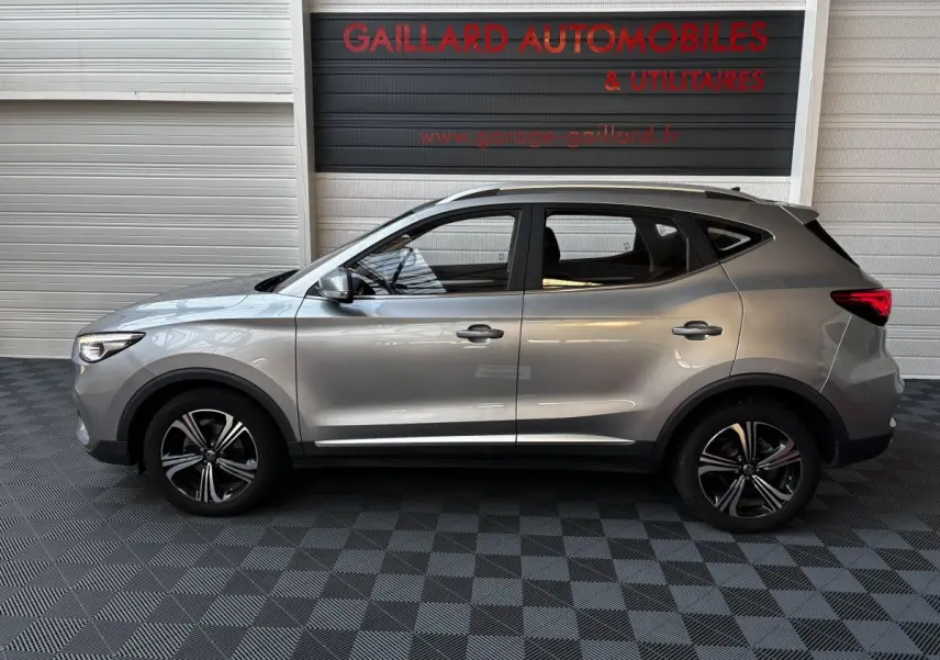 Vue de profil côté gauche d’un MG ZS gris clair 2022, avec jantes alliage et toit ouvrant visible.