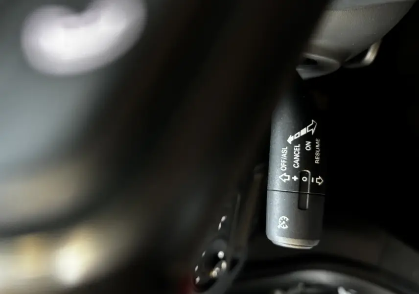 Gros plan sur la commande de régulateur de vitesse noire, à droite du volant d’un MG ZS gris clair 2022.