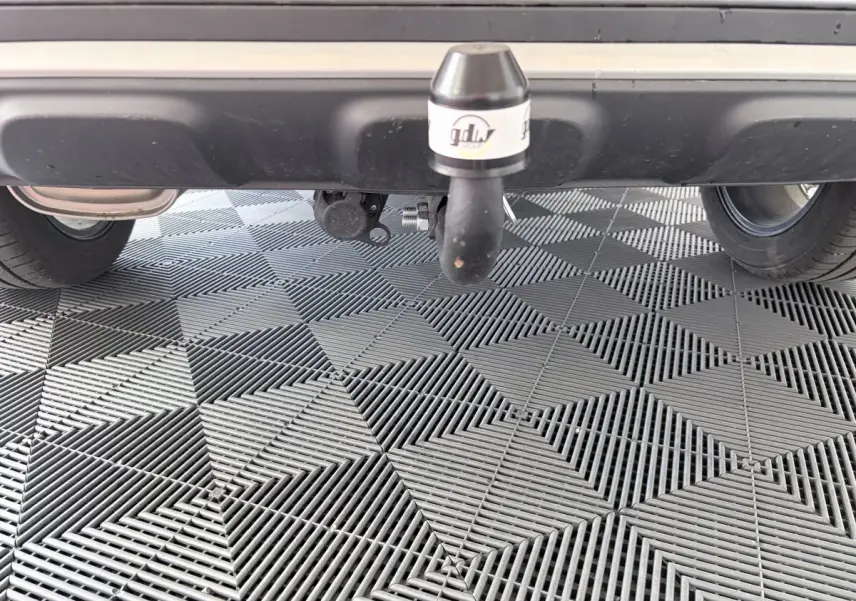 Vue rapprochée de l'attelage d'une MG ZS gris clair, sous le pare-chocs arrière sur sol carrelé.