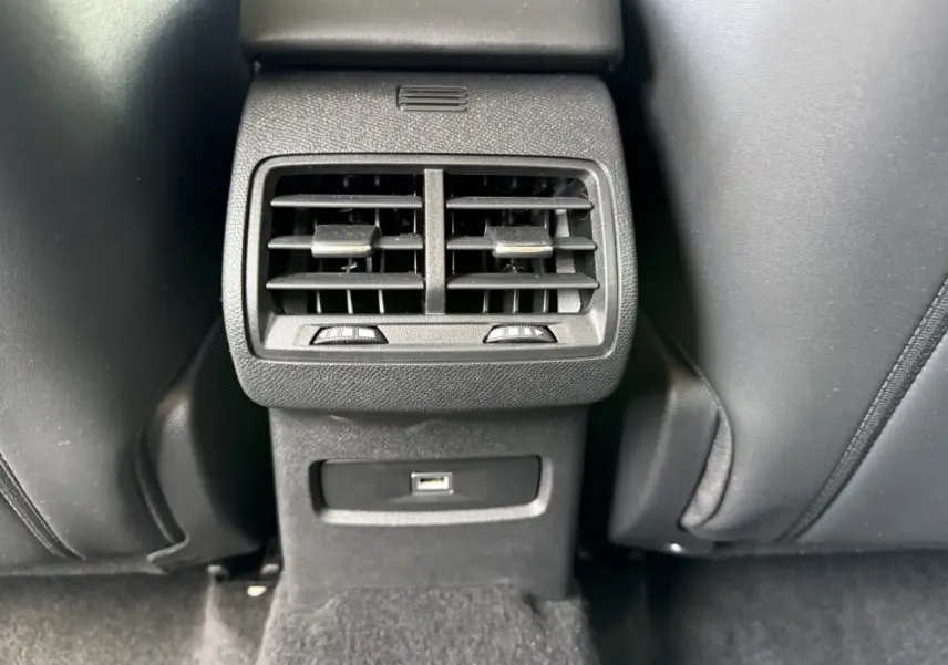 Vue rapprochée des aérateurs arrière noirs et prise USB entre les sièges avant en cuir noir du MG ZS gris clair.