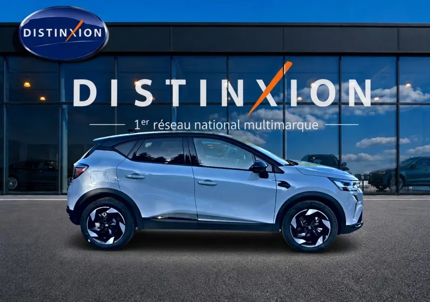 Profil droit du Renault Captur 2026 gris rafale avec jantes alu noires devant une vitrine Distinxion.