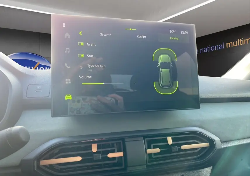 Écran tactile central affichant les réglages de sécurité et parking dans l’habitacle gris clair du Dacia Sandero Stepway.