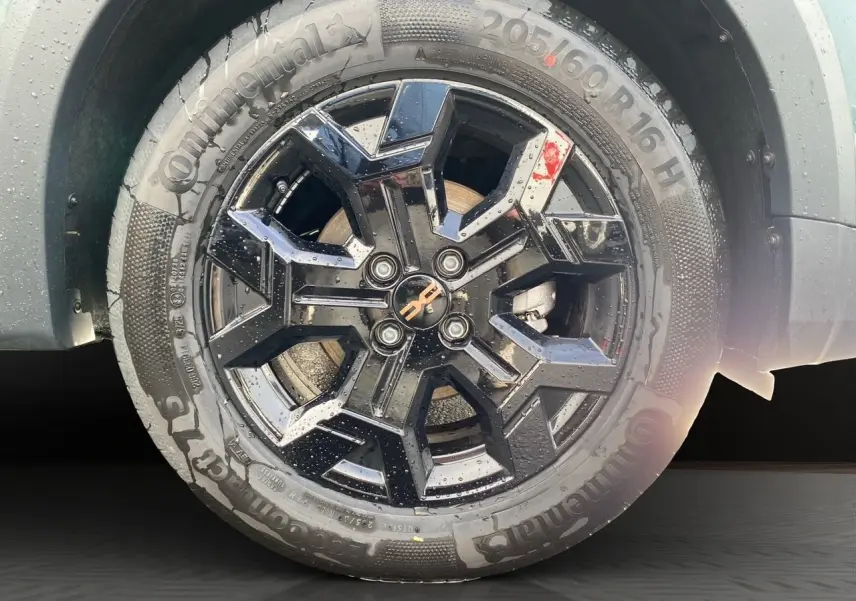 Gros plan sur la jante alliage noire 16 pouces Tamia Black d'une Dacia Sandero Stepway Vert Cèdre avec pneu Continental.