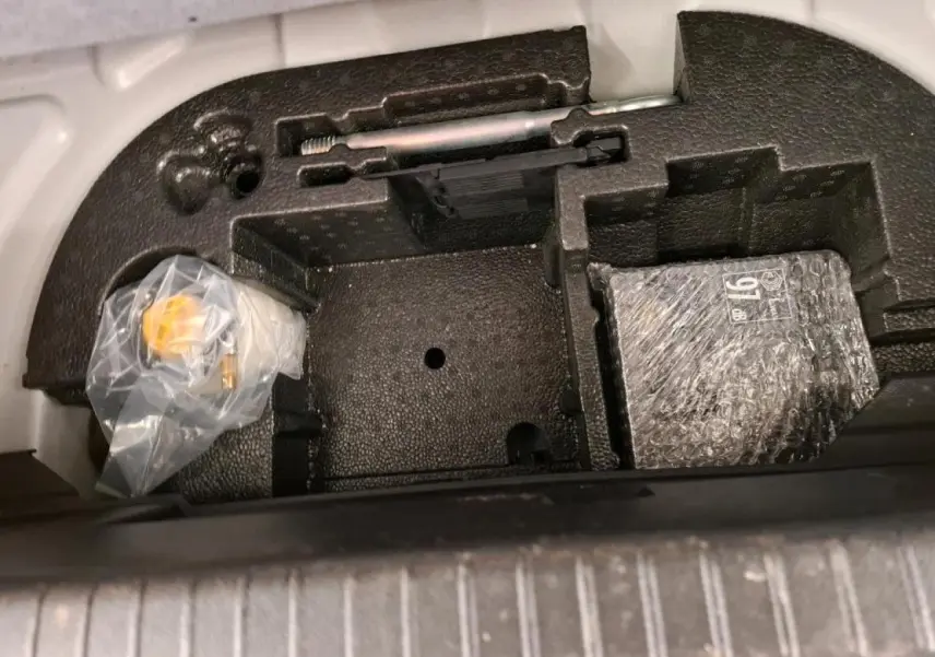 Coffre à outils et accessoires sous plancher de coffre de Peugeot 208 e-136 blanc, vue de dessus.